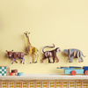 Colorful animal-shaped hooks on a yellow wall above a shelf with toys.